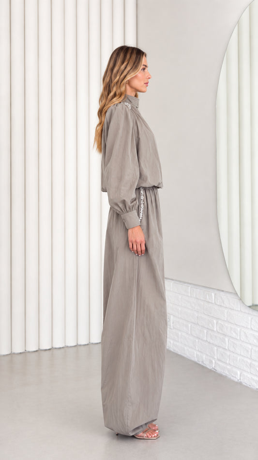 Side profile of model wearing taupe grey high-neck balloon-leg jumpsuit