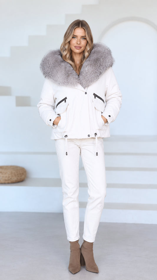 Front view of model wearing white hooded jacket with plush faux fur trim and matching white pants